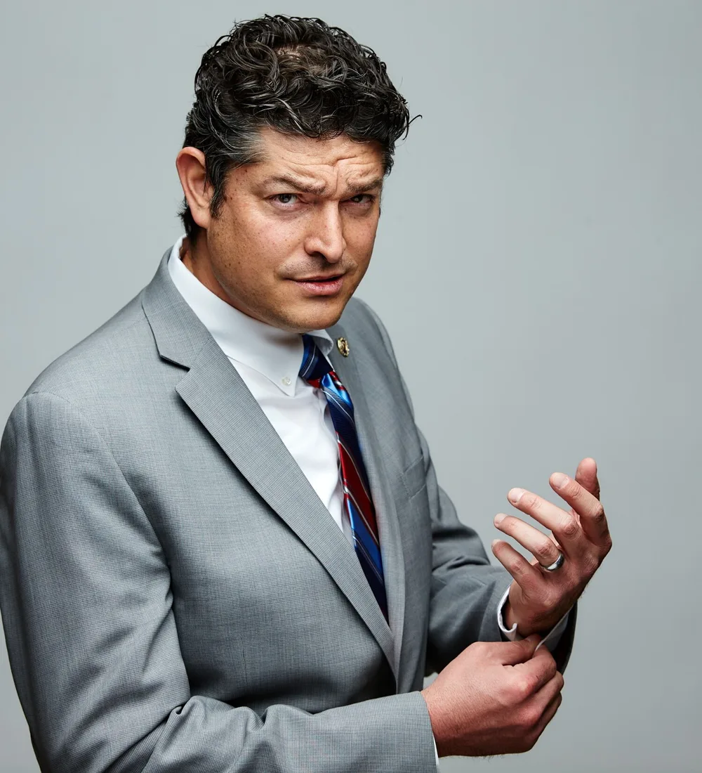 Adam Weiss raising one eyebrow at the camera while adjusting his cuff